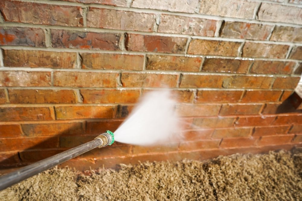 A high pressure water jet being used to clean weathered brickwork